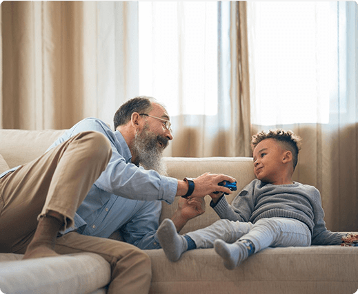 Grandfather and young boy playing together on a sofa, emphasizing family connections and care in a home environment.